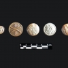 <p>Examples of military uniform buttons found during the 2005-2006 archeological survey of Davids Island. This group includes (left to right) a small sleeve button; a First World War machine gun company collar button; and three blouse, jacket or pocket buttons, including one dating to the Civil War (far right).</p>